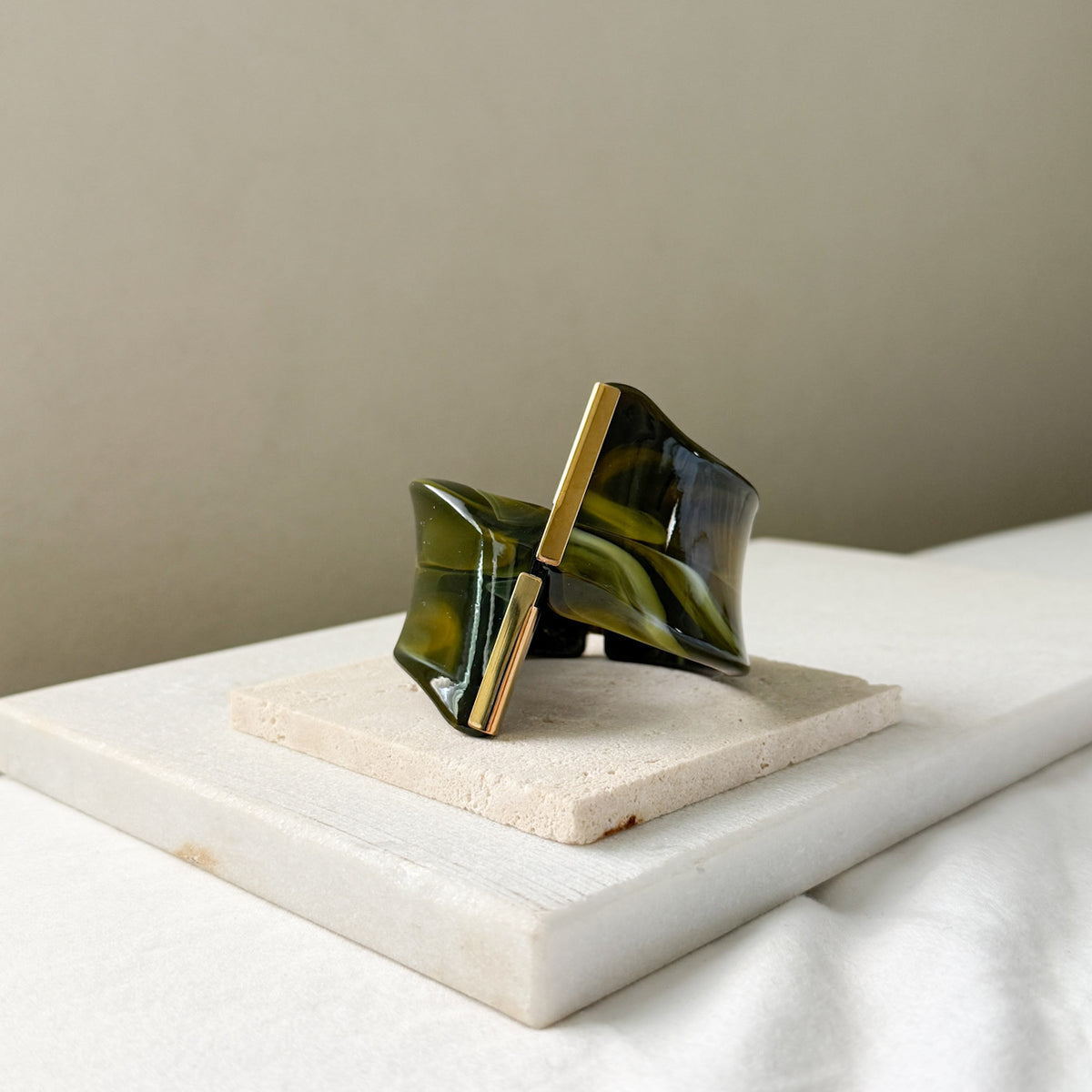 bracelet cuff with green and gold design on a marble surface. Gaia Sculptural Statement Bracelet - The Songbird Collection