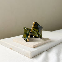 bracelet cuff with green and gold design on a marble surface. Gaia Sculptural Statement Bracelet - The Songbird Collection