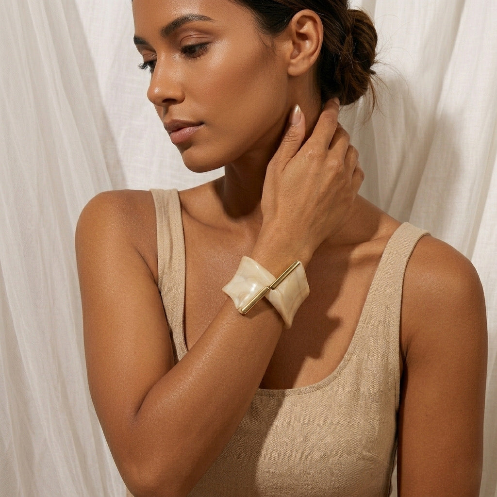 Woman wearing a beige bracelet against a white curtain background