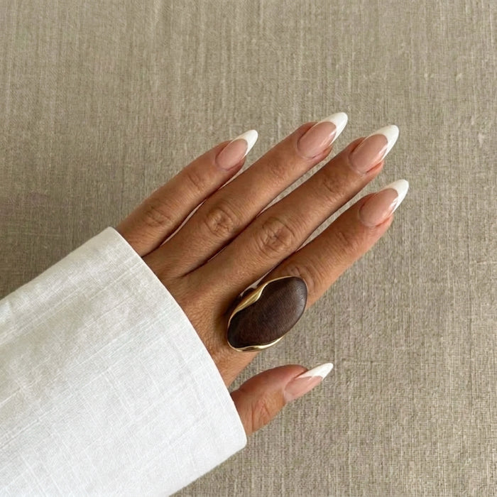 Hand wearing a brown ring with a beige background - Gaia_Sculptural_Statement_Ring_-_The_Songbird_Collection_-_dark wood