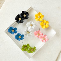 Set of colorful flower-shaped earrings on a clear stand with a white background