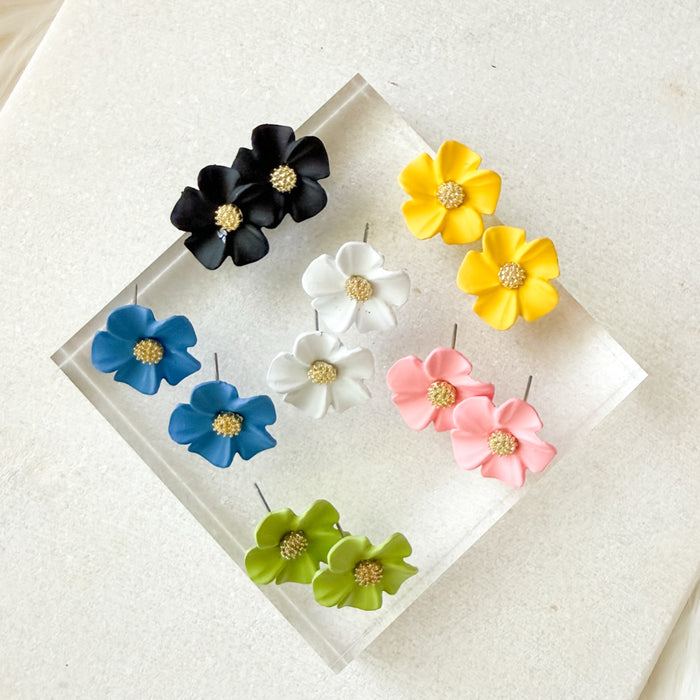 Set of colorful flower-shaped earrings on a clear stand with a white background