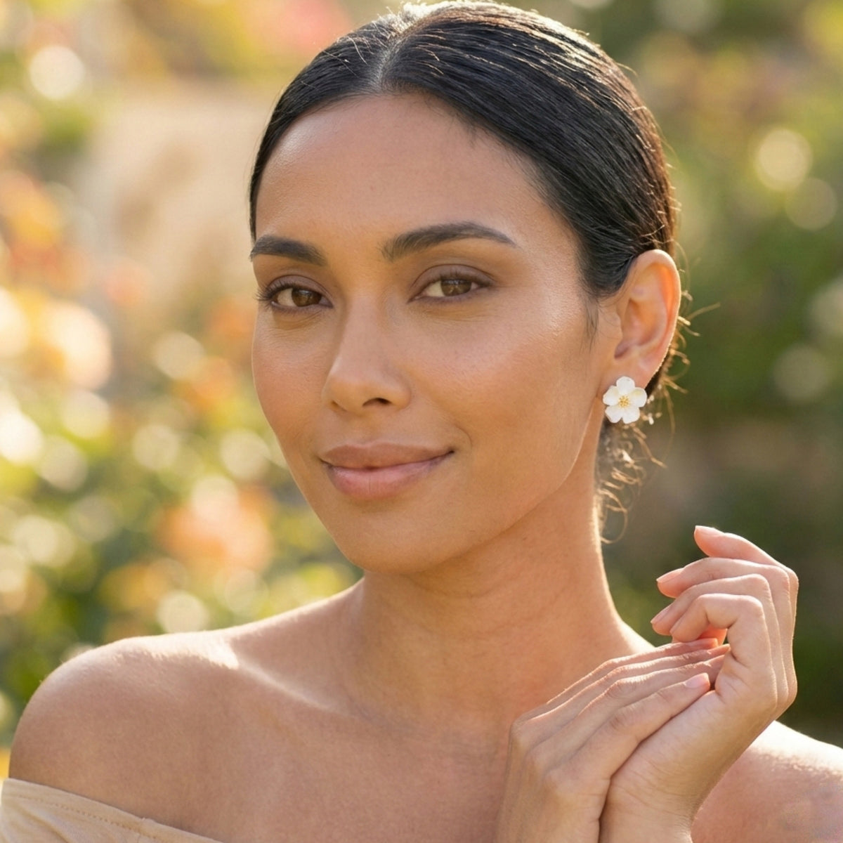 Woman with a white flower stud earring against a blurred natural background
