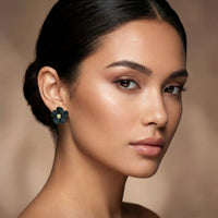 Close-up of a woman wearing a black floral  stud earring against a neutral background