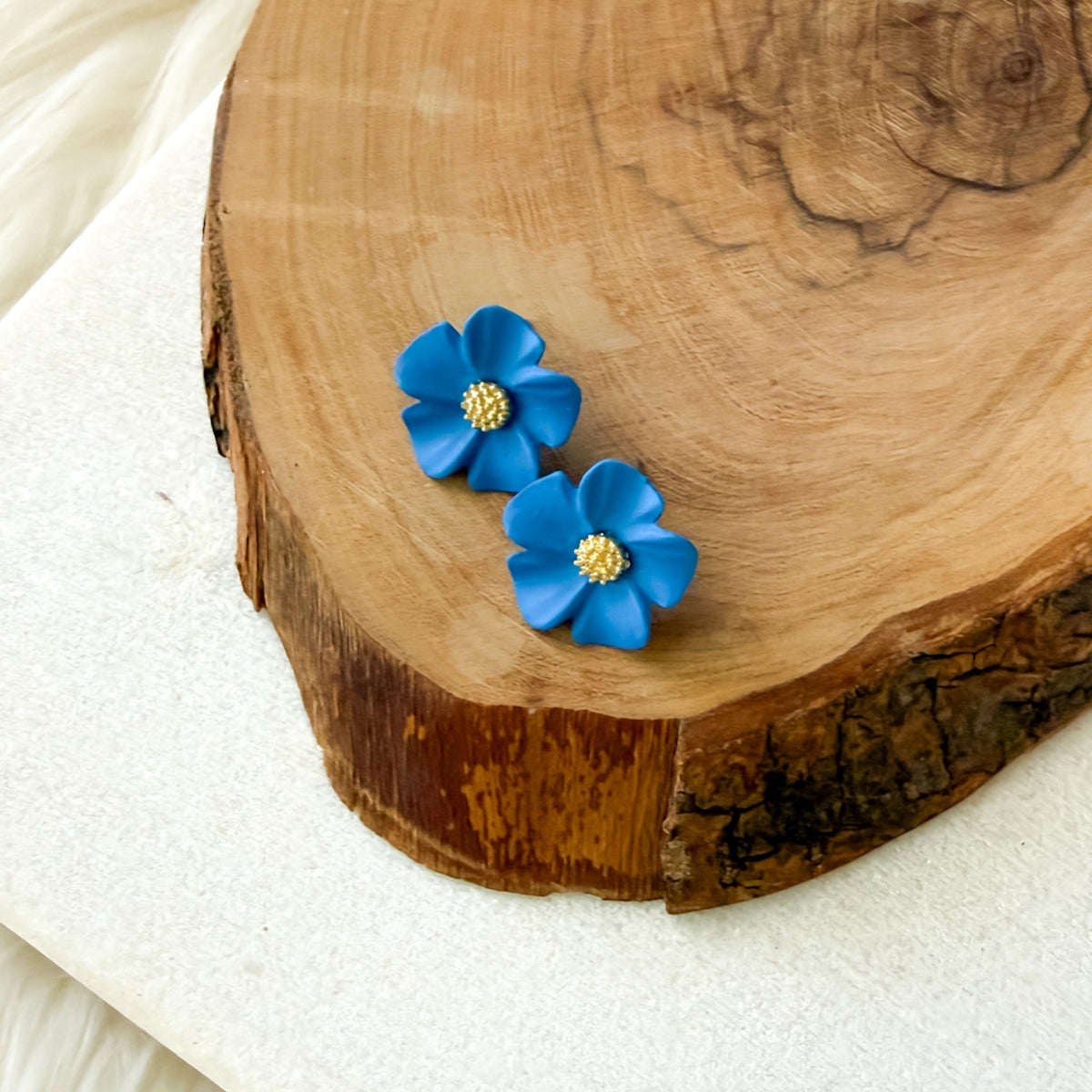 Blue flower-shaped earrings on a wooden surface