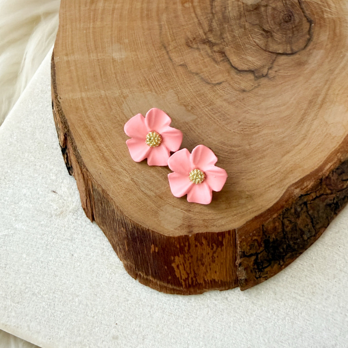 Pink flower-shaped earrings on a wooden surface