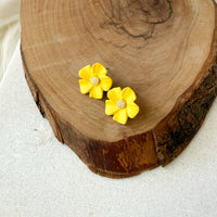 Yellow flower-shaped earrings on a wooden surface