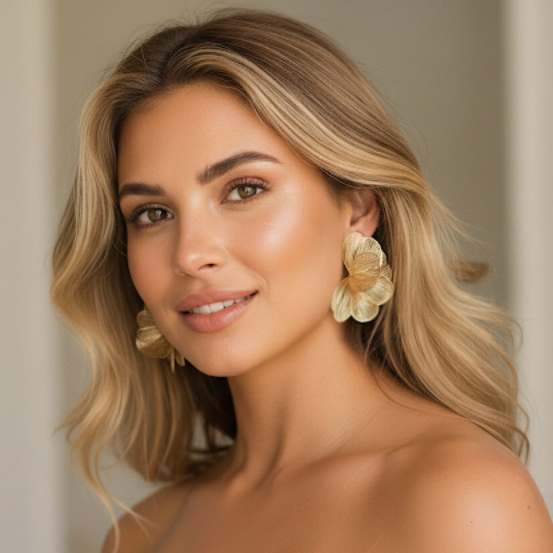 Woman wearing large floral earrings with a neutral background