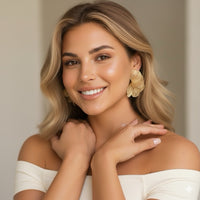 Woman wearing gold earrings with a neutral background
