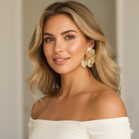 Woman wearing floral earrings against a neutral background