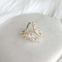 A hand showcasing a silver-colored chandelier ring with cubic zirconia on a finger, with multi-colored nails.