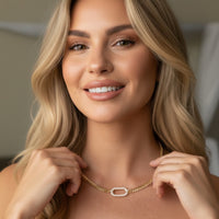 Woman wearing a gold necklace with a neutral background