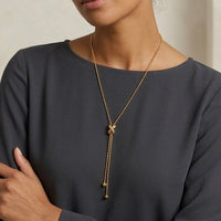Person wearing a gold necklace with a dark gray top - Infinity Knot Lariat Necklace - The Songbird Collection 
