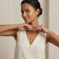 Woman wearing a gold necklace with a plain background - Infinity Knot Lariat Necklace - The Songbird Collection