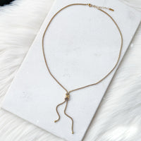 Gold necklace on a white marble surface Infinity Knot Lariat Necklace - The Songbird Collection