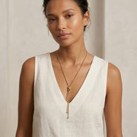 Woman wearing a gold necklace against a neutral background -  Infinity Knot Lariat Necklace - The Songbird Collection