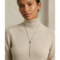 Woman wearing a beige turtleneck sweater with a long necklace against a neutral background - Infinity Knot Lariat Necklace - The Songbird Collection