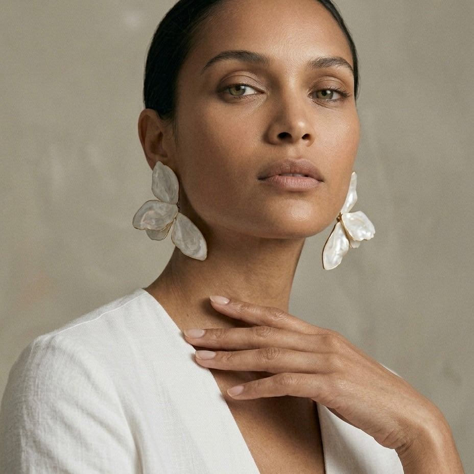 Woman wearing large, white floral earrings against a neutral background  Ivory_Lotus_Statement_Earrings_-_The_Songbird_Collection