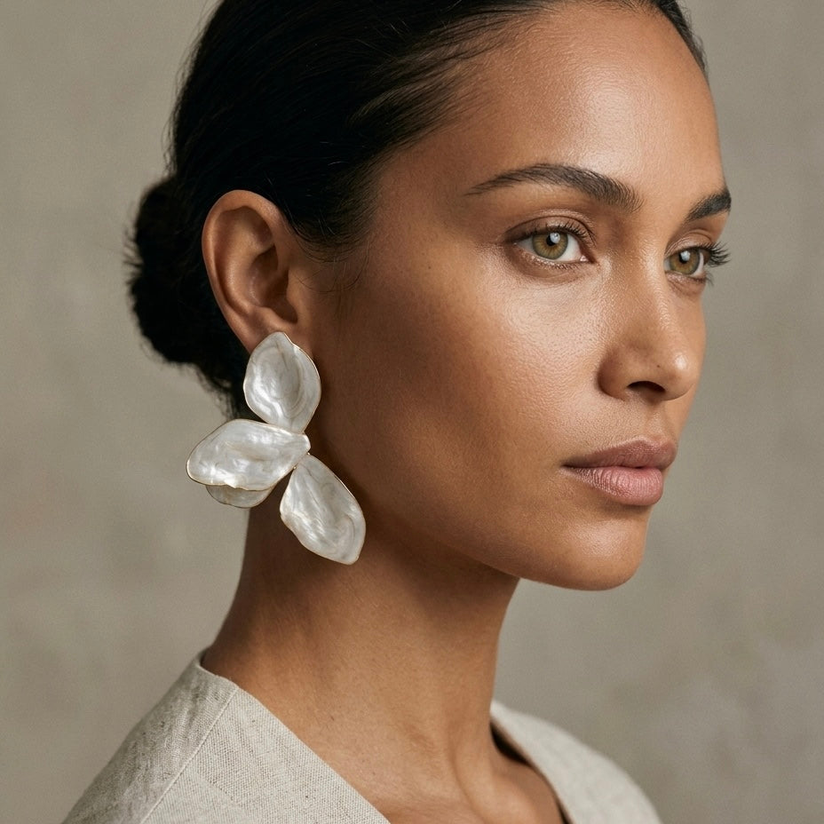 Woman wearing large, white floral earrings against a neutral background  Ivory_Lotus_Statement_Earrings_-_The_Songbird_Collection