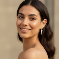 Woman with a smile wearing earrings against a neutral background