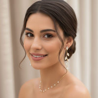 Woman wearing a pearl necklace and earrings with a neutral background