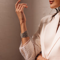 A person wearing a silver multi-layer rhinestone bracelet on their wrist, with the bracelet reflecting light and detail.