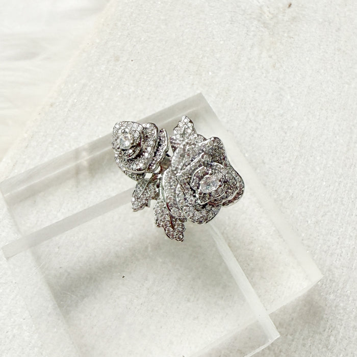 Silver rose-shaped ring with gemstones on a white background