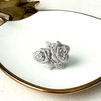 Silver rose-shaped jewelry on a white plate with gold rim