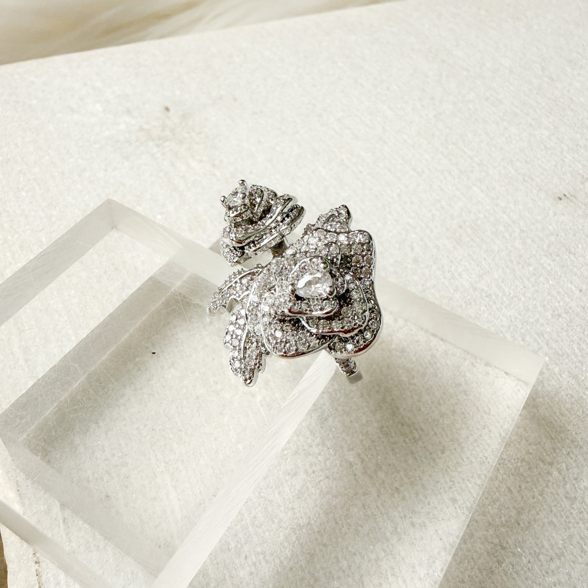 Silver rose ring with clear stones on a white surface