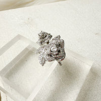 Silver rose ring with clear stones on a white surface