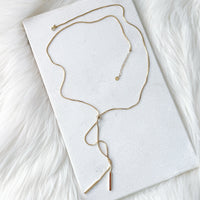 Gold necklace on a white card with a white fur background