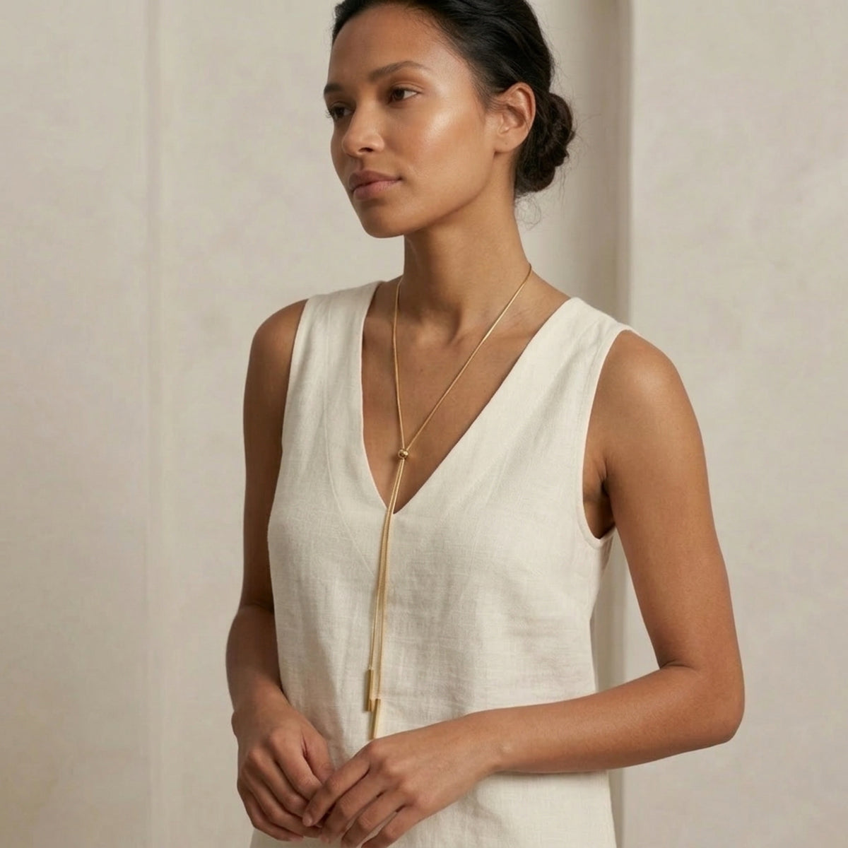 Woman wearing a white sleeveless top with a gold zipper against a beige background - Linearity Lariat Necklace - The Songbird Collection