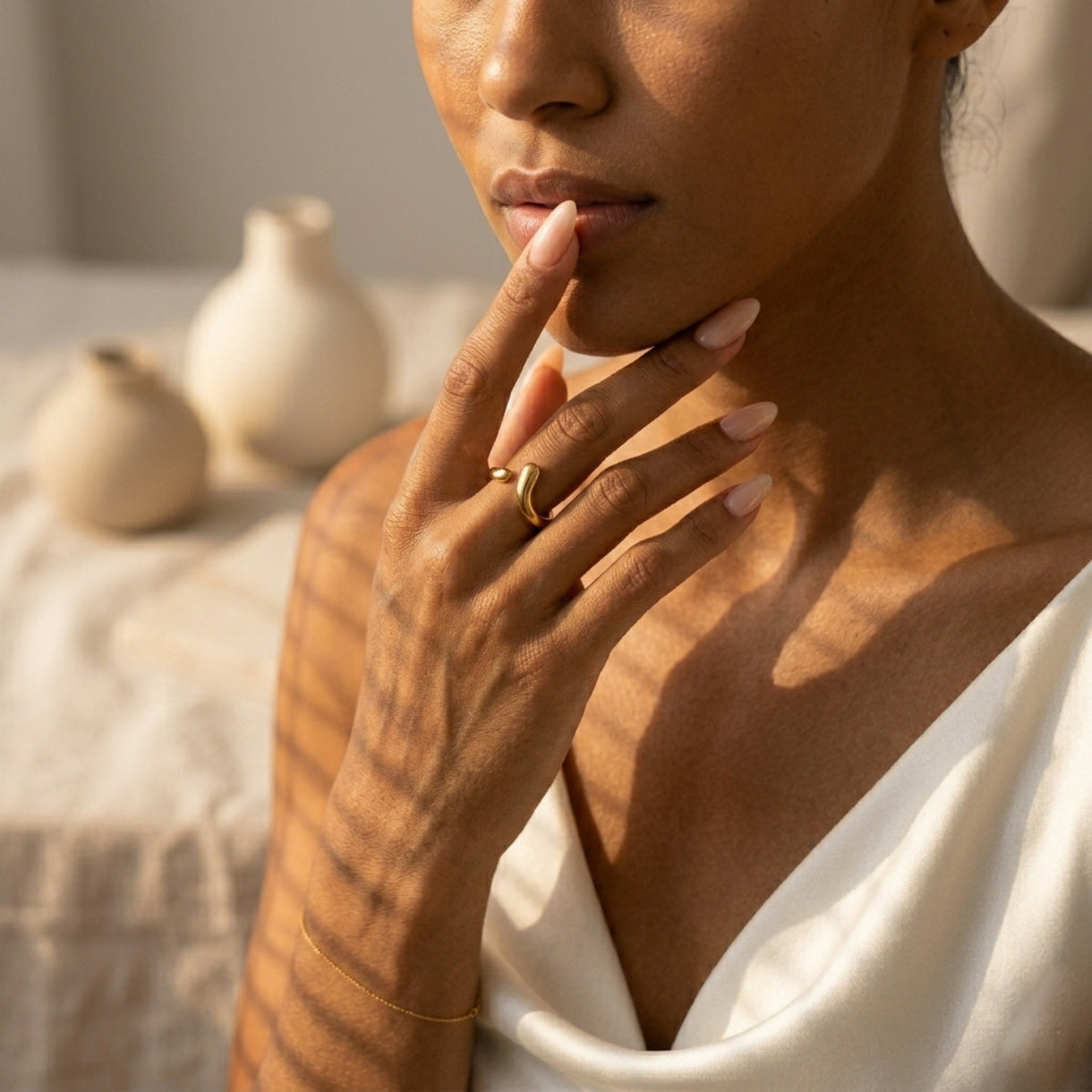 Woman wearing a gold ring with a neutral background  Liquid Curve Ring - The Songbird Collection