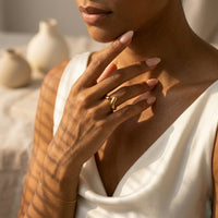 Woman wearing a gold ring on her hand with a neutral background  Liquid Curve Ring - The Songbird Collection