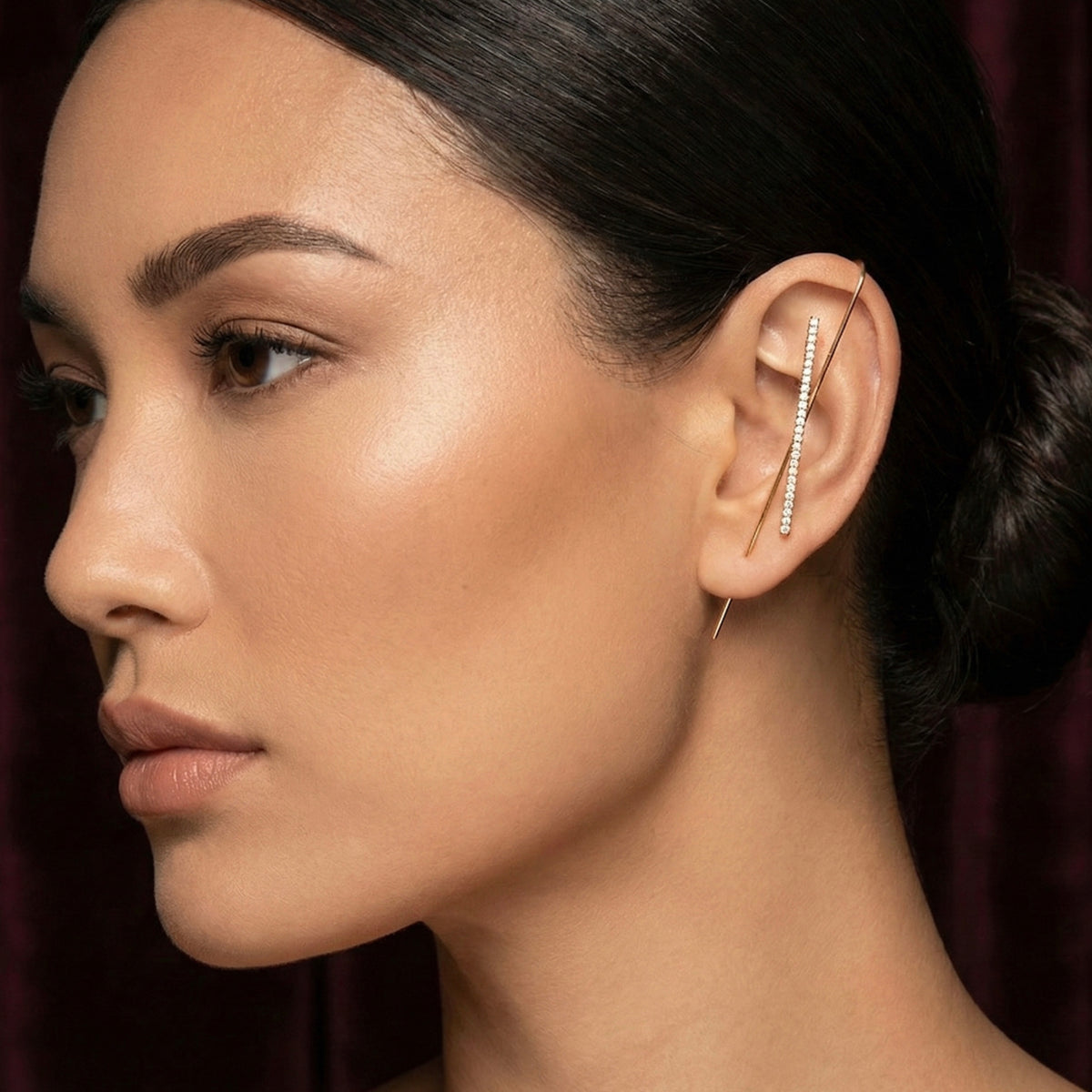 Close-up of a woman wearing a diamond studded ear hook/ear cuff/ earring with a dark background