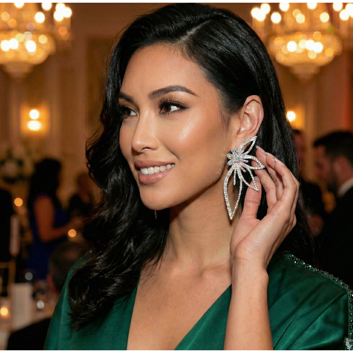 Woman wearing a green dress and large floral petal shaped rhinestone statement earrings in an elegant indoor setting