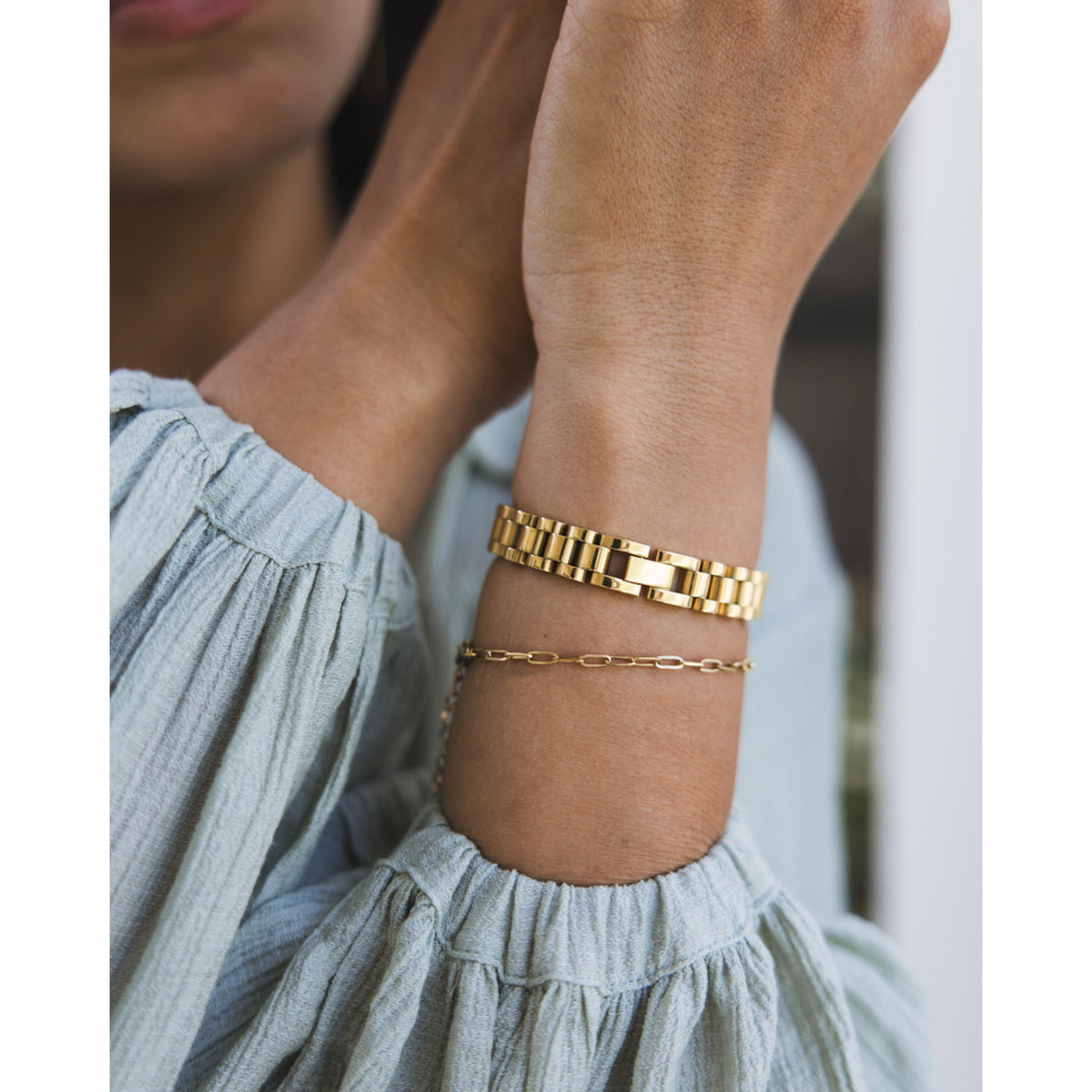 A person's wrist wearing a gold-plated chunky chain bracelet.