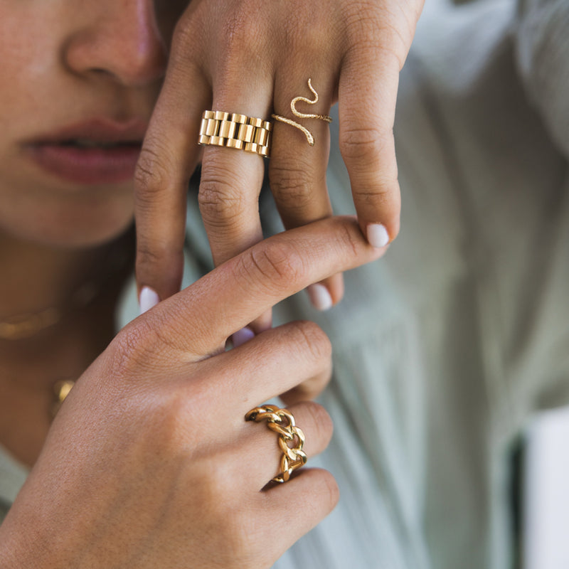 A person's hands showcasing a gold-plated chunky chain ring, with a focus on the jewelry.