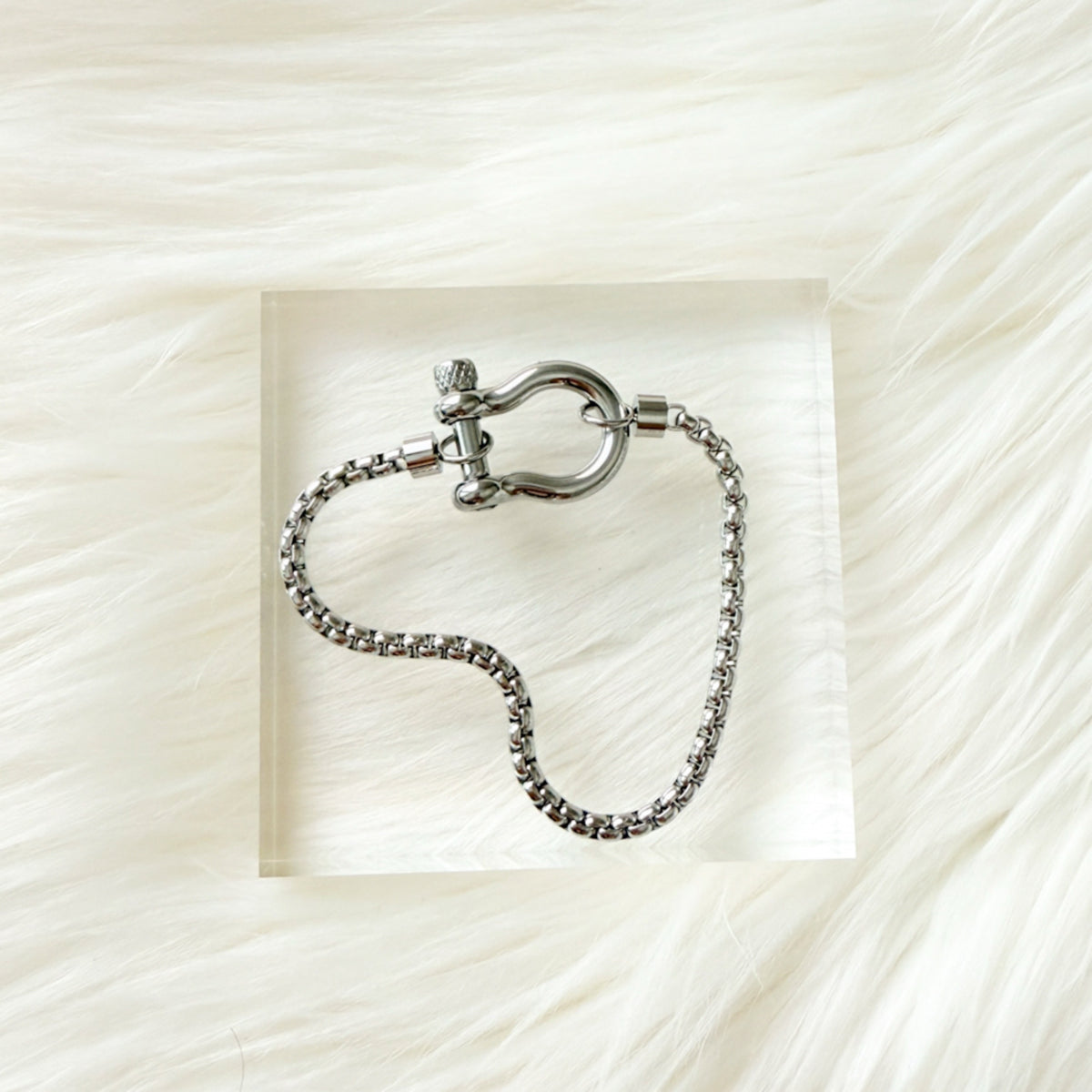 Silver chain bracelet with clasp on a textured white background