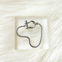Silver chain bracelet with clasp on a textured white background