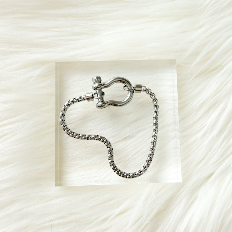 Silver chain bracelet with clasp on a textured white background