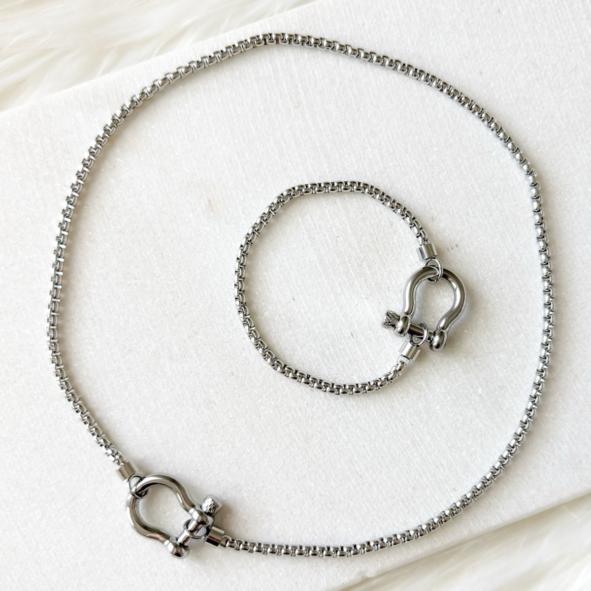 Silver necklace and bracelet set on a white background