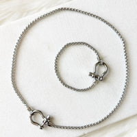 Silver necklace and bracelet set on a white background