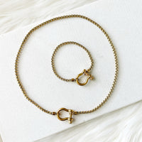 Gold chain necklace with clasp on a white surface