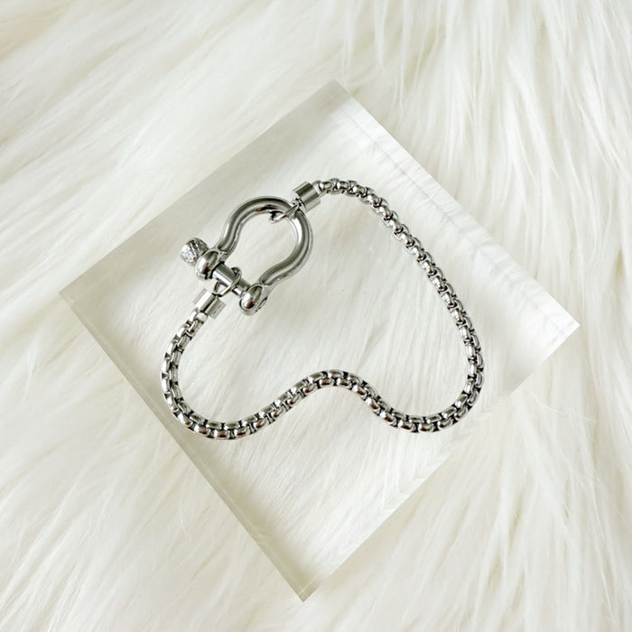 Silver bracelet with chain design on a white fabric background