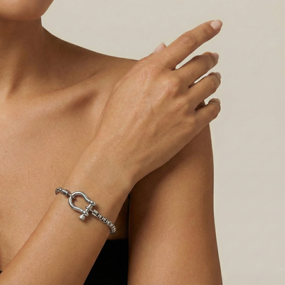 Silver horse shoe lock bracelet on a person's wrist with a neutral background Lucky_Shackle_Bracelet_stainless_steel_The_Songbird_Collection