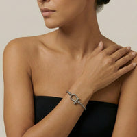 Woman wearing a silver horseshoe bracelet on her wrist with a neutral background Lucky_Shackle_Bracelet_stainless_steel_The_Songbird_Collection