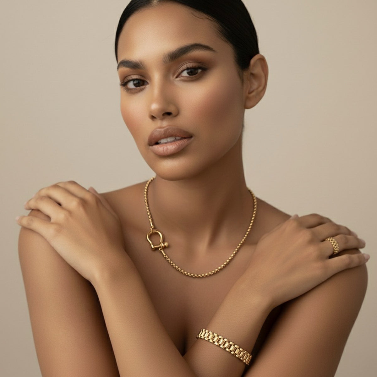 Woman wearing horseshoe shaped necklace and watch chain link bracelet gold jewelry against a beige background