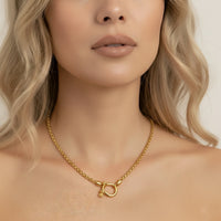 Gold necklace worn by a model with a neutral background