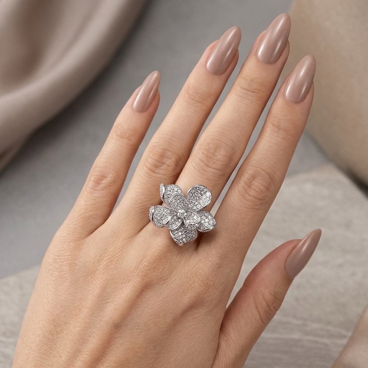 Flower-shaped diamond ring on a hand with beige nail polish